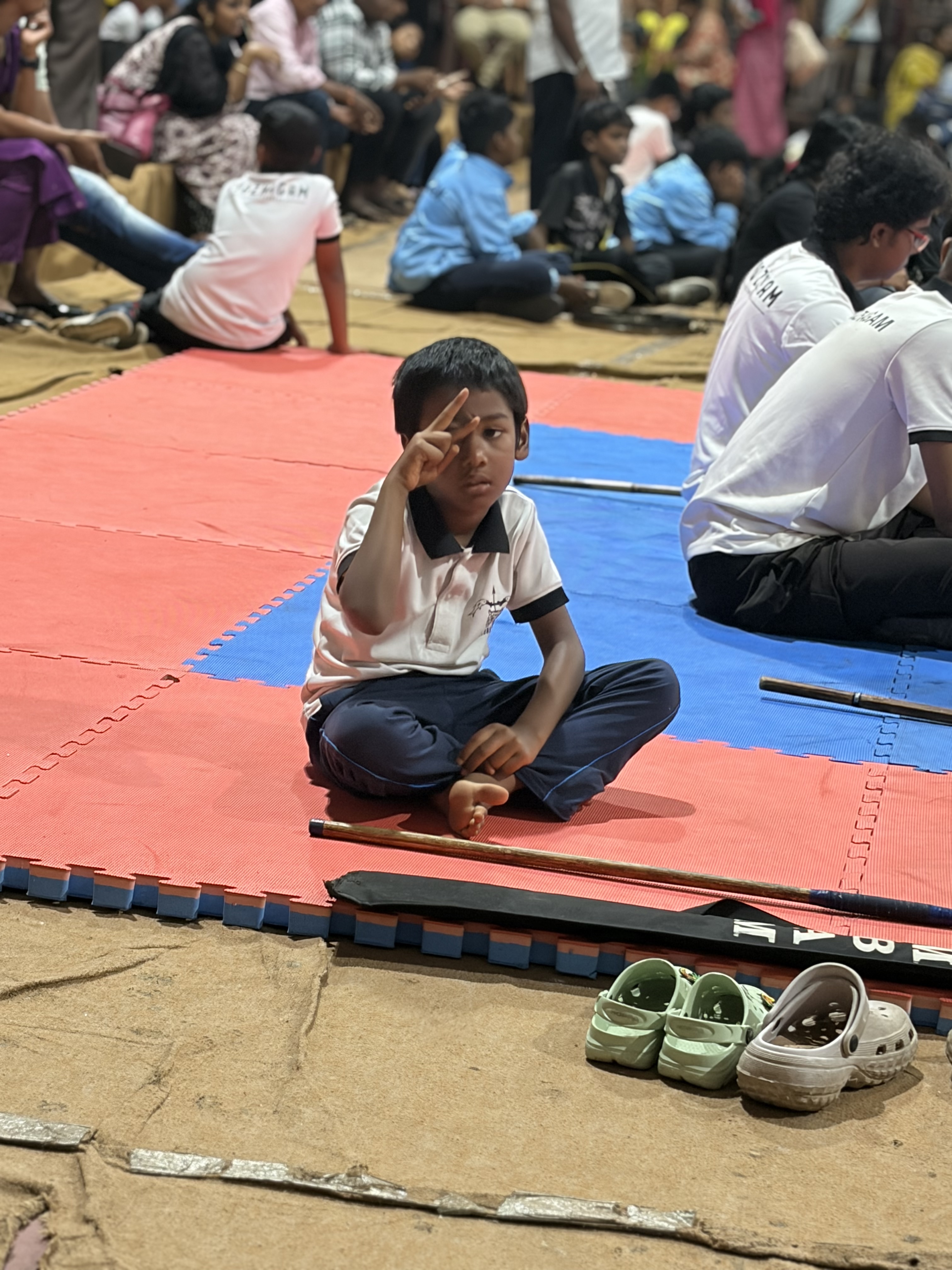 Prithvi, seated, one finger raised to the brow in a Silambam salute